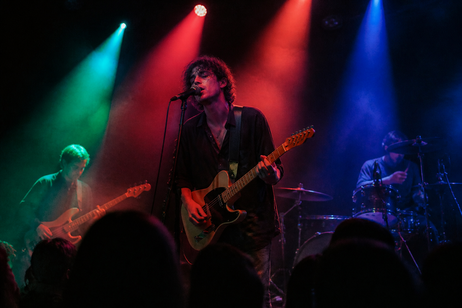A live band performing on stage with dramatic lighting.